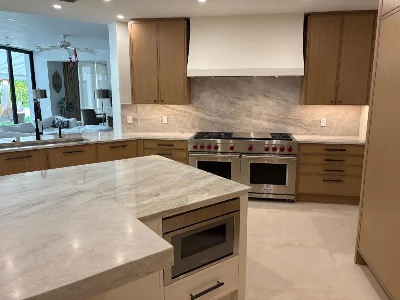 Another finished kitchen, with light stone counters and a stone backsplash behind the range.